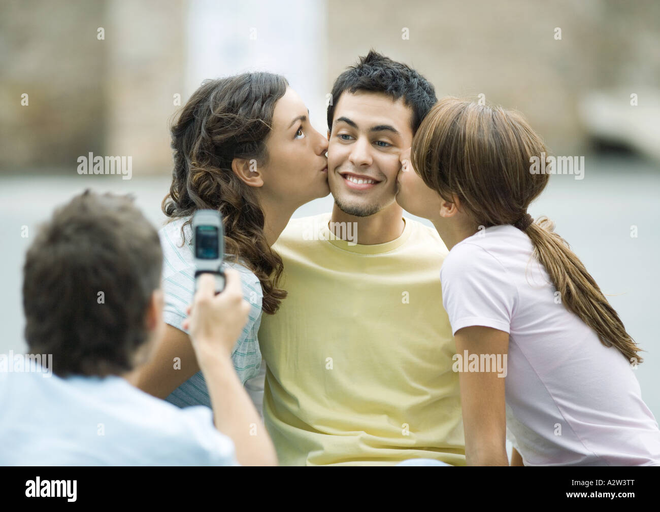 Teen Mädchen Jungen Wangen küssen, während der zweite junge Foto nimmt Stockfoto