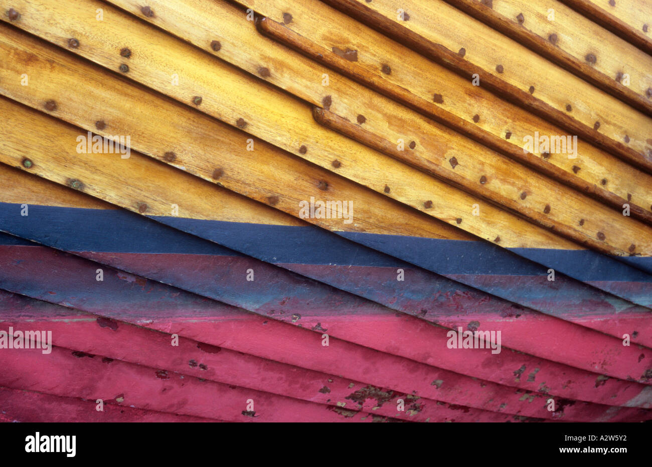 Blick von unten auf Teil des Rumpfes Holzboot mit klar lackierten Hölzern und blau und rosa Fleck am und unter Wasser-Linie Stockfoto