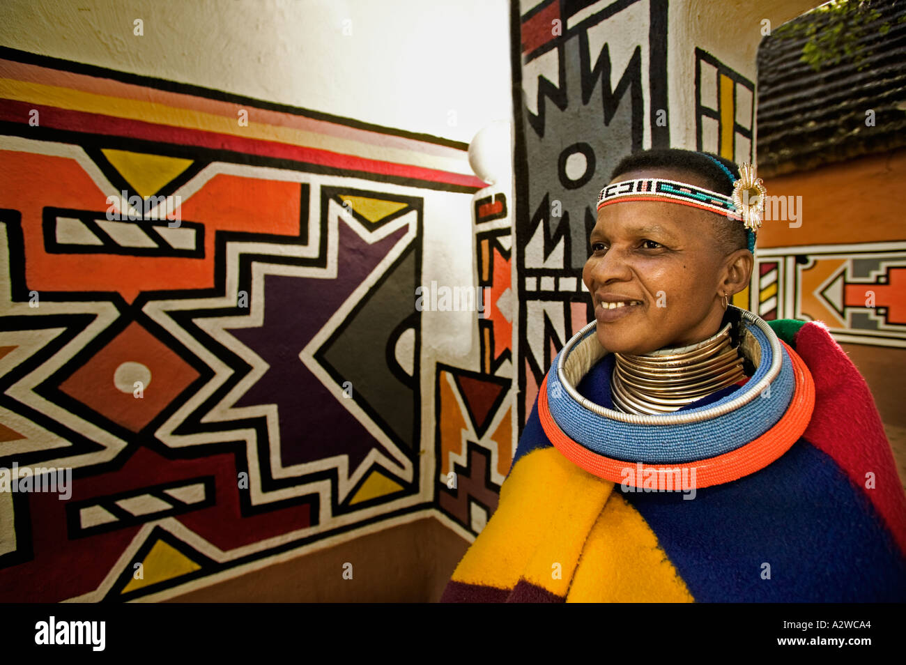 Ndebele Frau in Tracht gekleidet verheiratete Frau traditionelle geometrischen Wandmalereien im Hintergrund Südafrika Stockfoto