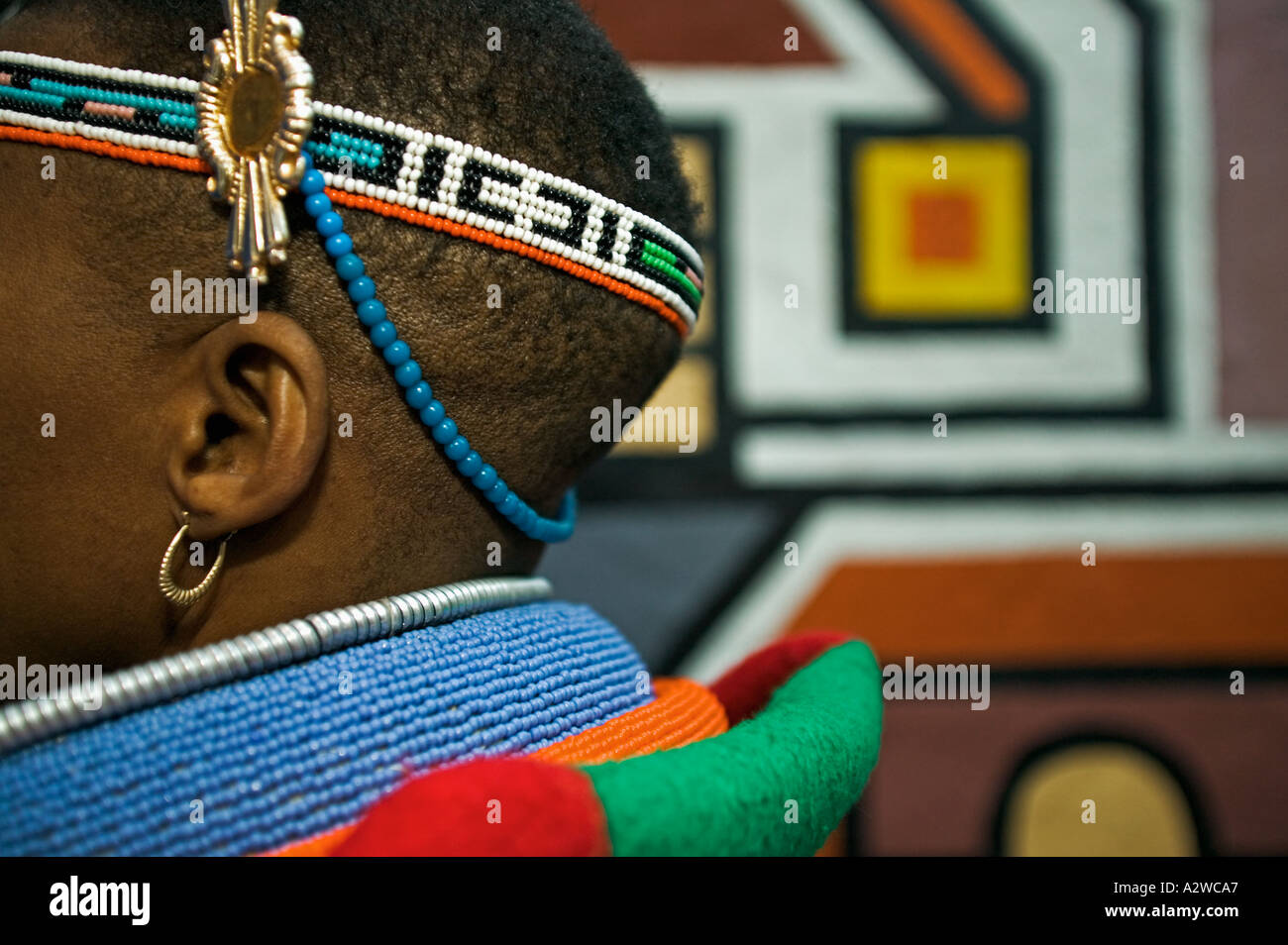 Ndebele Frau in Tracht gekleidet verheiratete Frau traditionelle geometrischen Wandmalereien im Hintergrund Südafrika Stockfoto
