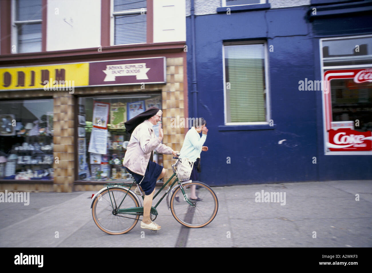 Nonne winken beim Radfahren Fahrrad entlang shopping Straße Carrickmacross an der Grenze zu Nord-Irland 1993 Stockfoto