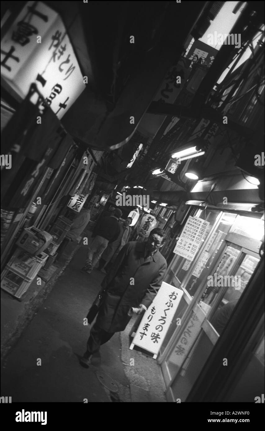 Salaryman geht durch eine Gasse voller Restaurants, hinter Shinjuku Station, Tokio, Japan, Asien. Stockfoto