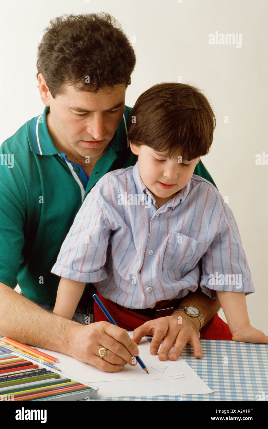 Indoor Nahaufnahme des erwachsenen Mannes zeigen junge Kind wie ein Bild zu zeichnen. Stockfoto