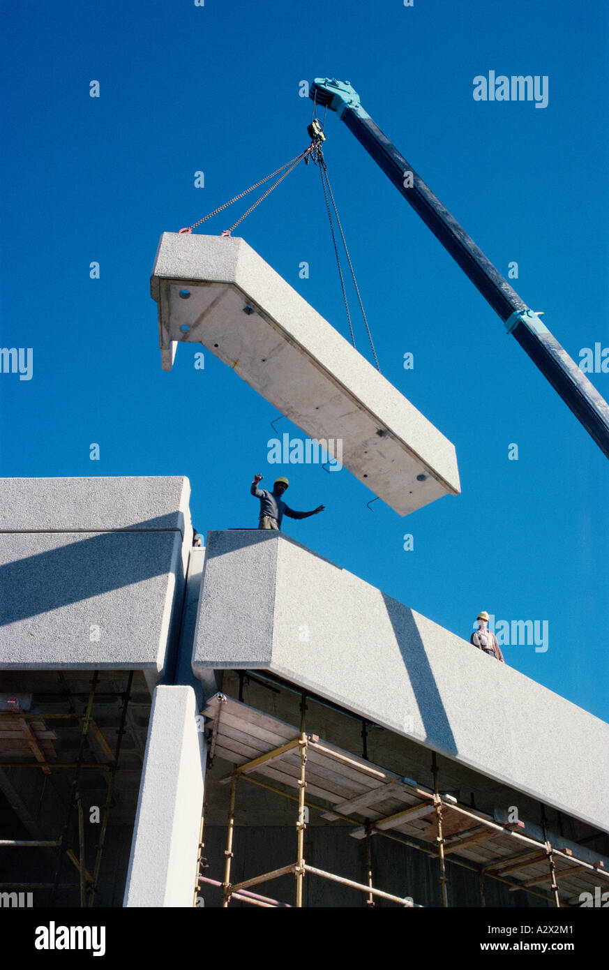 Bauindustrie. Arbeiter am Hochhaus Regie Kranführer Positionierung große konkrete Abschnitt. Stockfoto