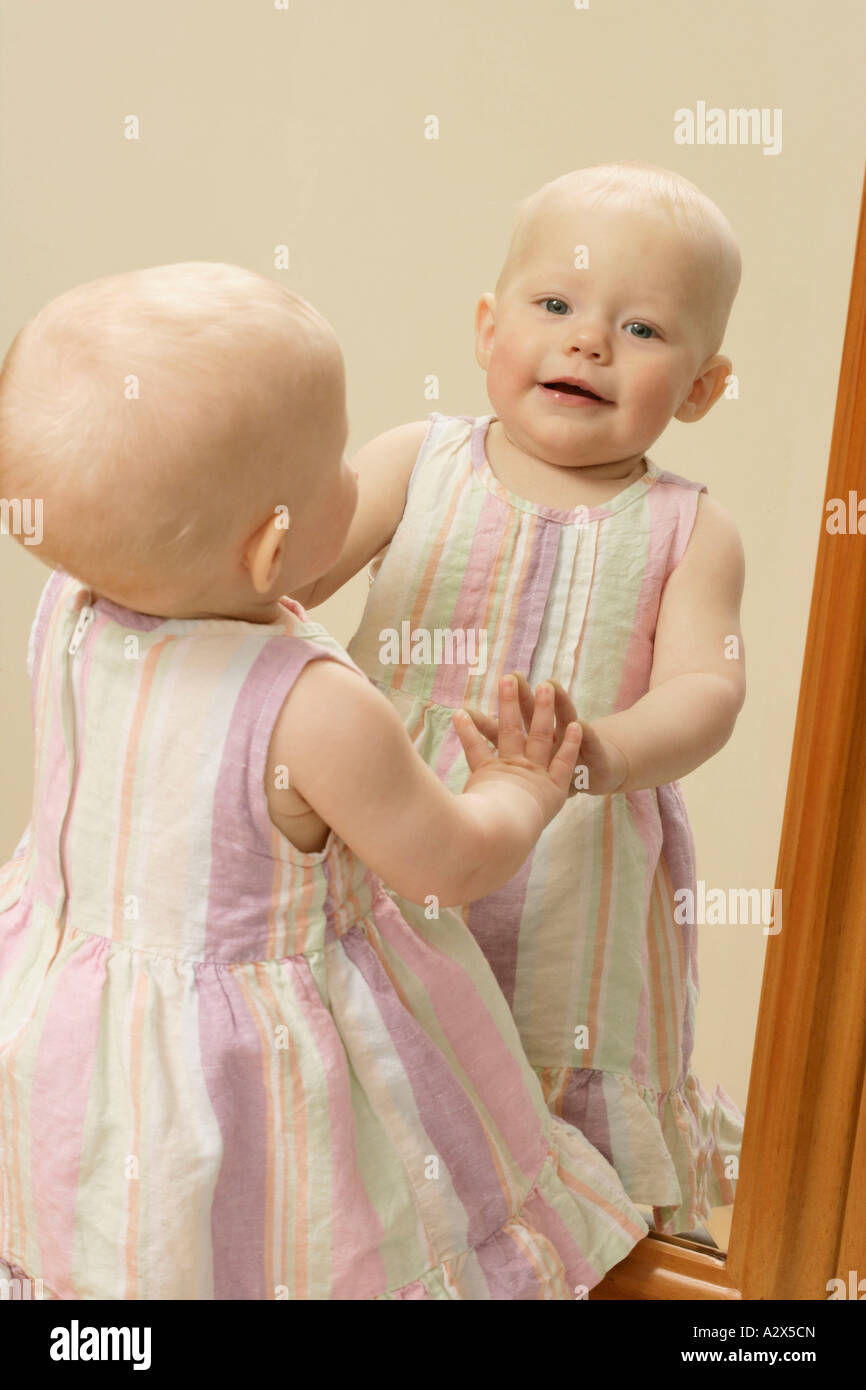 Niedliche Baby Lachen als sie schaut sich im Spiegel. Stockfoto