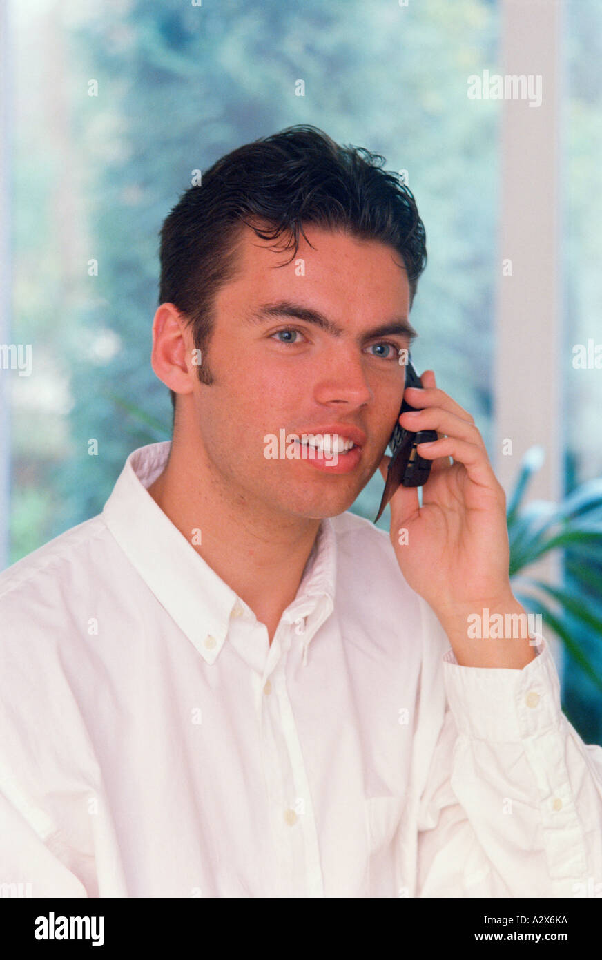 Junger Mann mit Handy "Telefon im Haus. Stockfoto