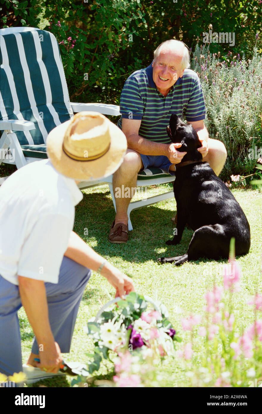 Senioren. Ehepaar im Ruhestand in ihrem Garten mit ihrem Hund. Stockfoto