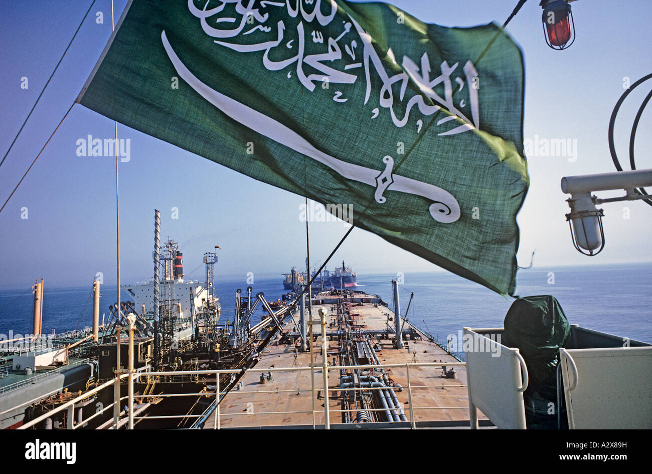 Saudi-Arabische Flagge fliegt über Schiffsbeladung Öl. "Es ist ein Gott außer Gott" verkündet, mit dem Schwert unter ihm. Stockfoto