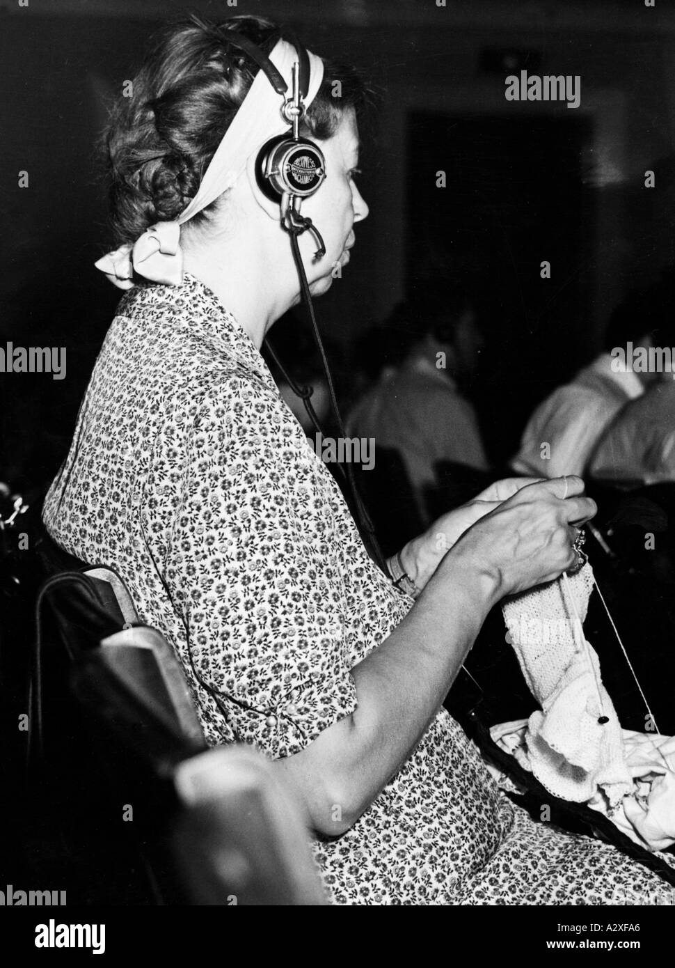 Die First Lady der Vereinigten Staaten, Frau Franklin D Roosevelt, schenkte ihr keine ungeteilte Aufmerksamkeit auf das Verfahren auf dem 2. Weltjugendkongress am 21. August 1938 ermöglichte es ihr die moderne Rundfunktechnik, dem sprachlichen Babel zu folgen von den 500 Delegierten aus 55 Ländern per Hörer beim gleichzeitigen Stricken Eingeschraenkte Aufmerksamkeit schenkt sterben First Lady der Vereinigten Staaten Frau Franklin D Roosevelt dem geschehen des 2 Weltjugendkongresses am 21. August 1938 die Moderne Uebertragungstechnik ermoeglicht ihr zu stricken und gleichzeitig dem Sprachengewirr der 500 Stockfoto