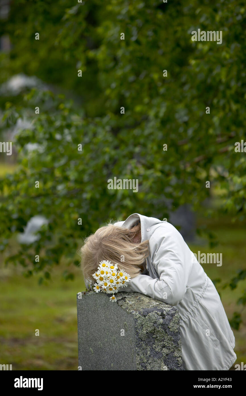 Senior der 50er Jahre 60er Jahre kaukasischen Frau mit Gänseblümchen legt Kopf auf Granit Grab Stein Marker Stockfoto