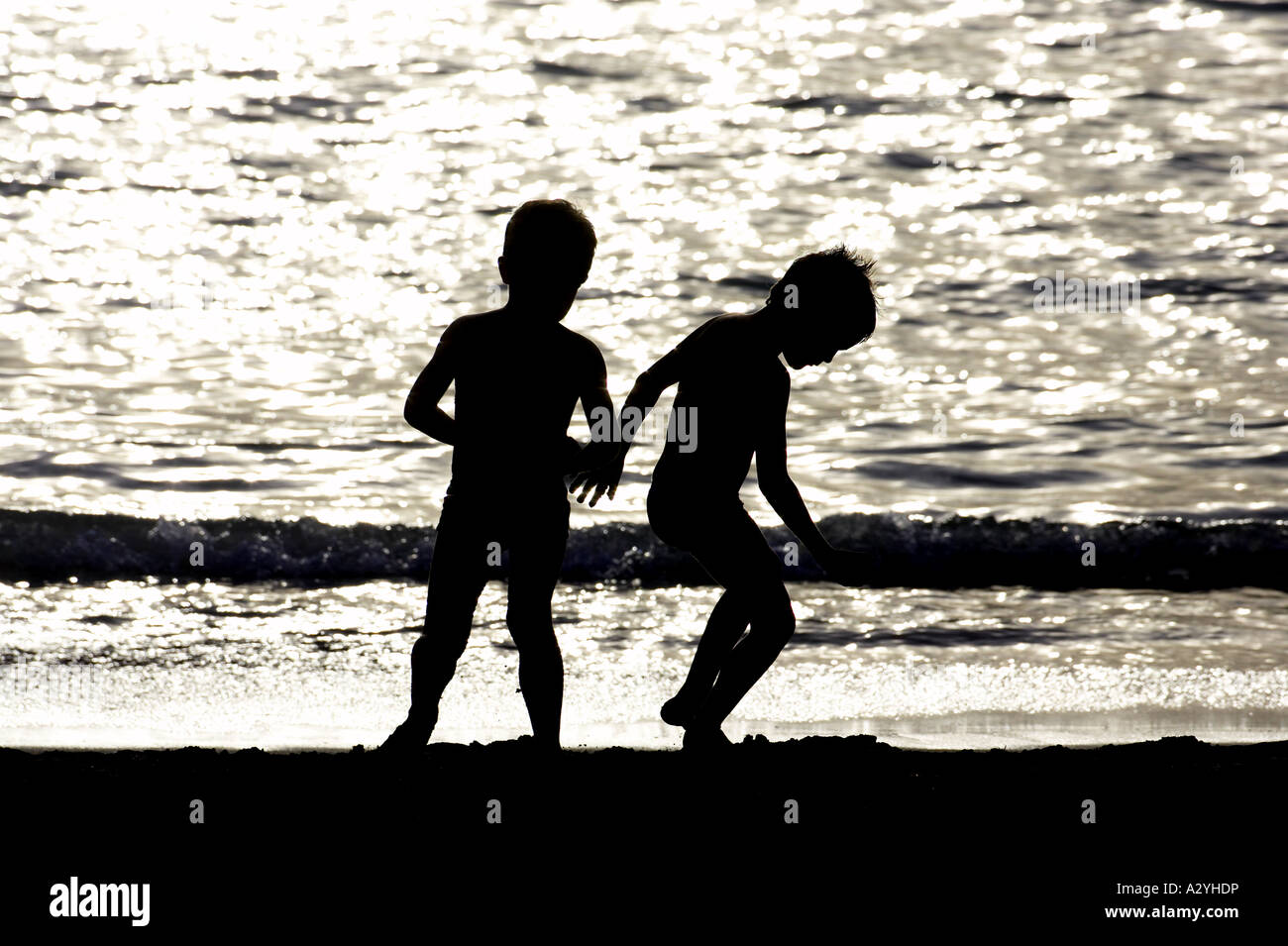 zwei junge Burschen in der Silhouette spielen am Ufer des Strandes am Playa de Las Americas Teneriffa Kanaren Spanien Stockfoto