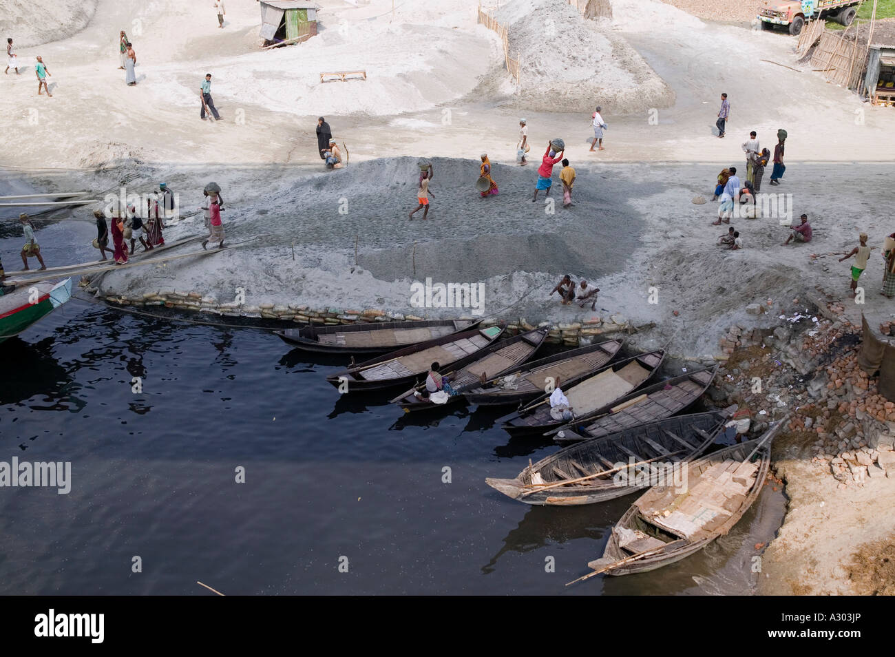 Arbeiter tragen schwere Körbe Sand auf ihre Köpfe aus dem Boot an den Strand entlang der Straße zum Savar in Bangladesch Stockfoto