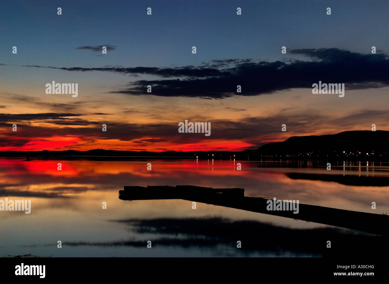 Ein roter Sonnenuntergang spiegelt sich auf eine perfekt noch Lagune mit einem Steg am Carleton Quebec Stockfoto