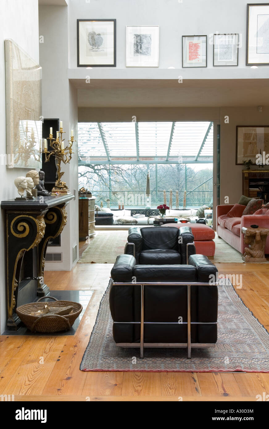 Offenen Wohnraum mit zwei schwarzen Ledersessel und Kaminsims Stück in Penthouse-Wohnung Stockfoto