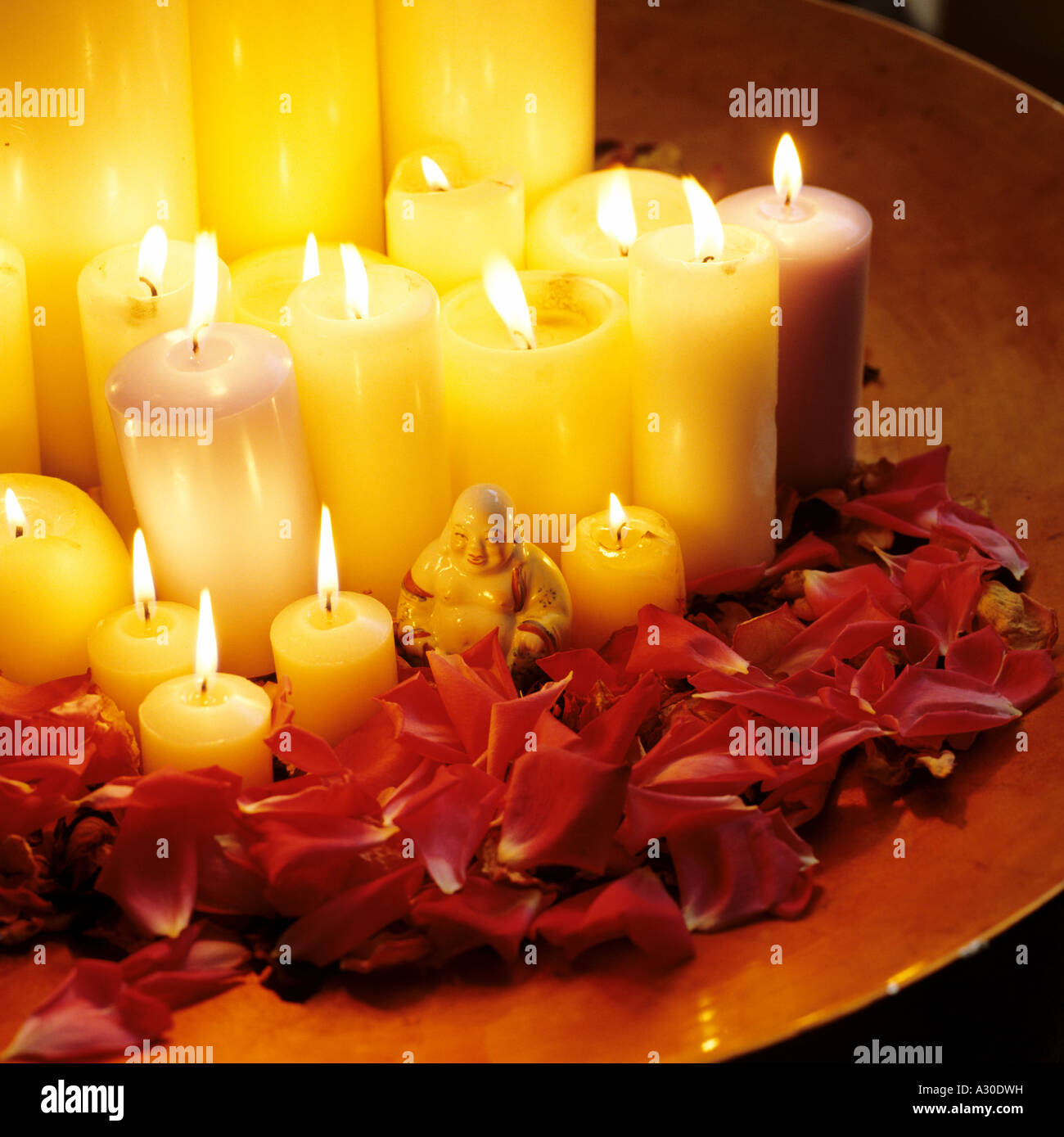 Kerzen in einer Schüssel mit Rosenblüten und eine Buddha-statue Stockfoto