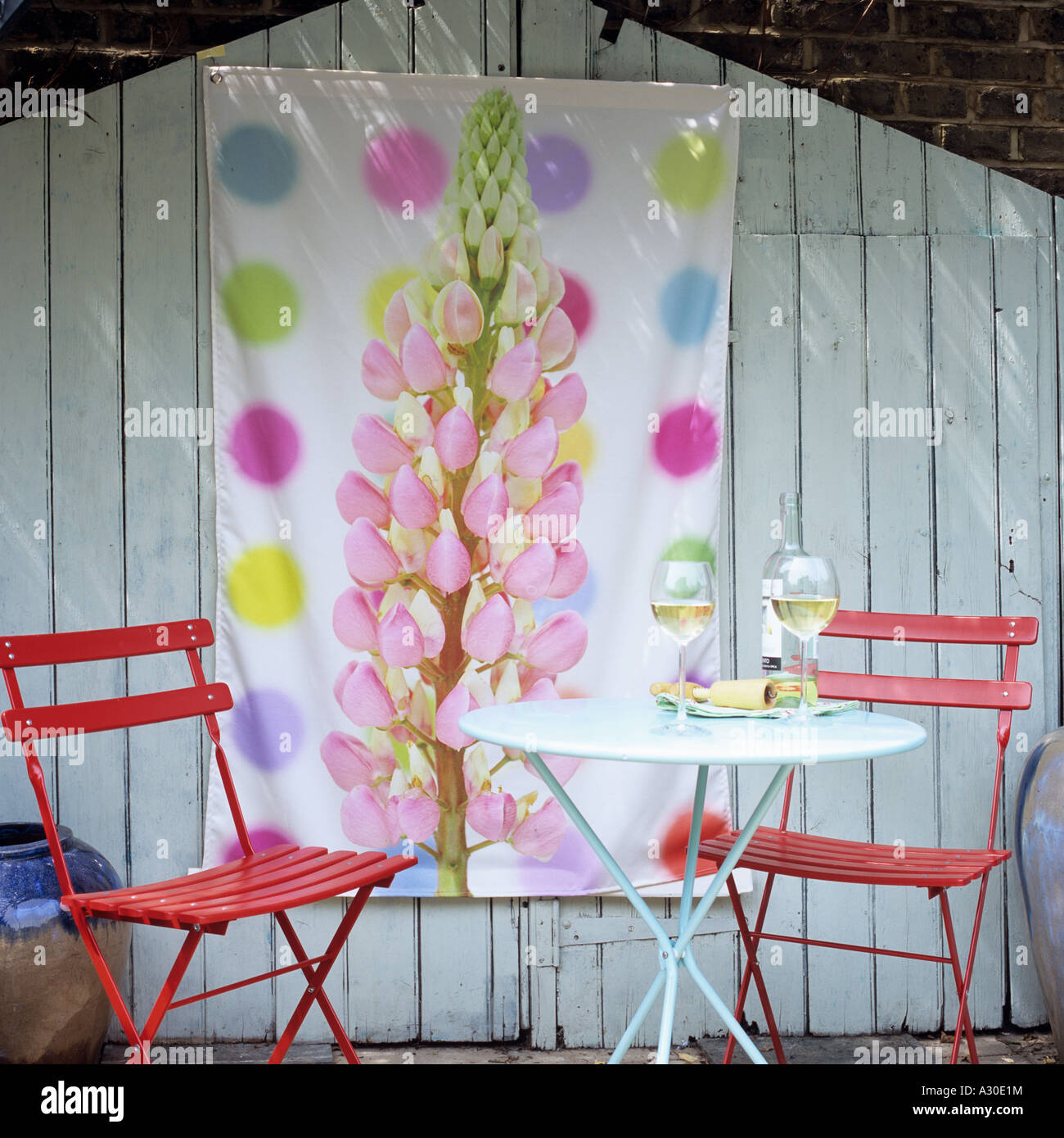 Gartentisch und Stühle vor Holzschuppen getäfelte Tür mit dekorativen Lupin Bild Stockfoto