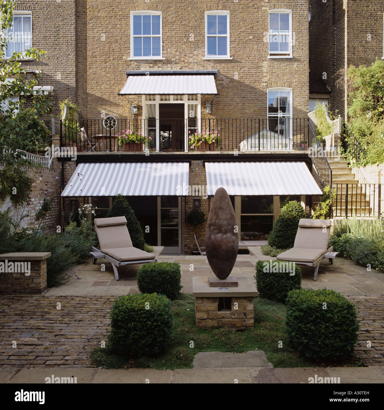 ein moderner Garten von einem Londoner Stadthaus mit Markisen und Sonnenliegen Stockfoto