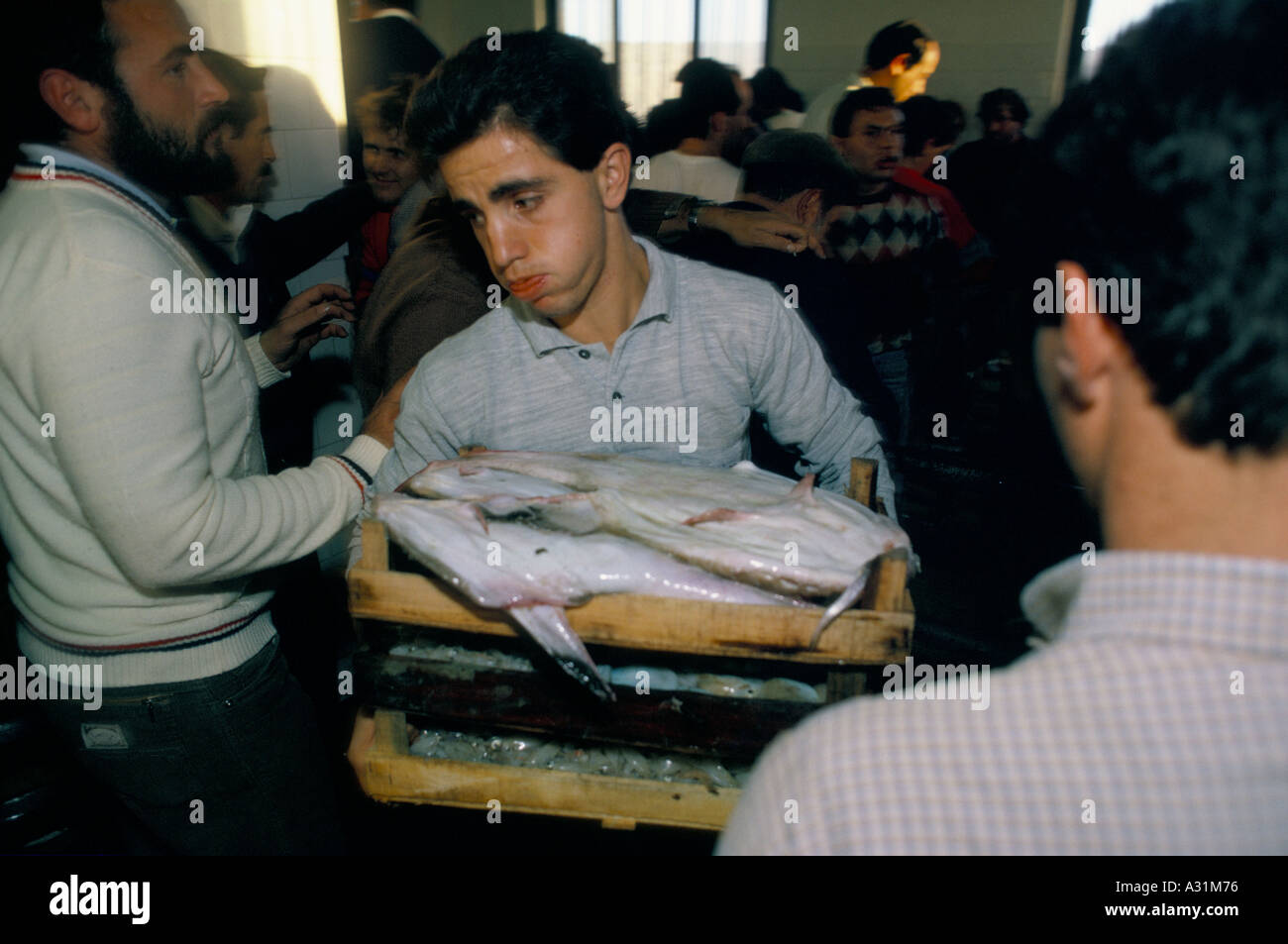 eine müde aussehenden Mann Hauche ihm über die Wangen, als er trägt ein Tablett mit Fische durch eine belebte drängen sich Sciacca-Sizilien Stockfoto