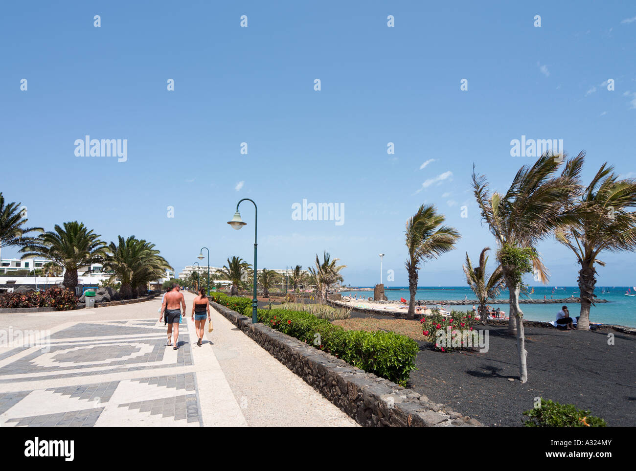 Paar zu Fuß entlang der Promenade am Strand von Playa de Las Cucharas, Costa Teguise, Lanzarote, Kanarische Inseln, Spanien Stockfoto