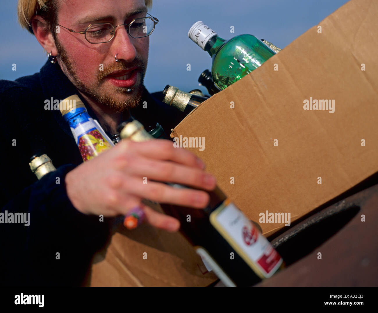 Person in den Zwanzigern recycling Bierflaschen Recycling Einheit North Wales UK Stockfoto