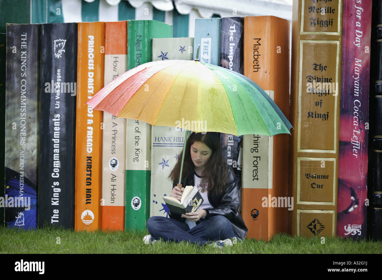 Ein Besucher der Hay on Wye Buchausstellung in Powys, Wales, lesen vor eine Anzeige von Oversize Bücher im Regen Stockfoto