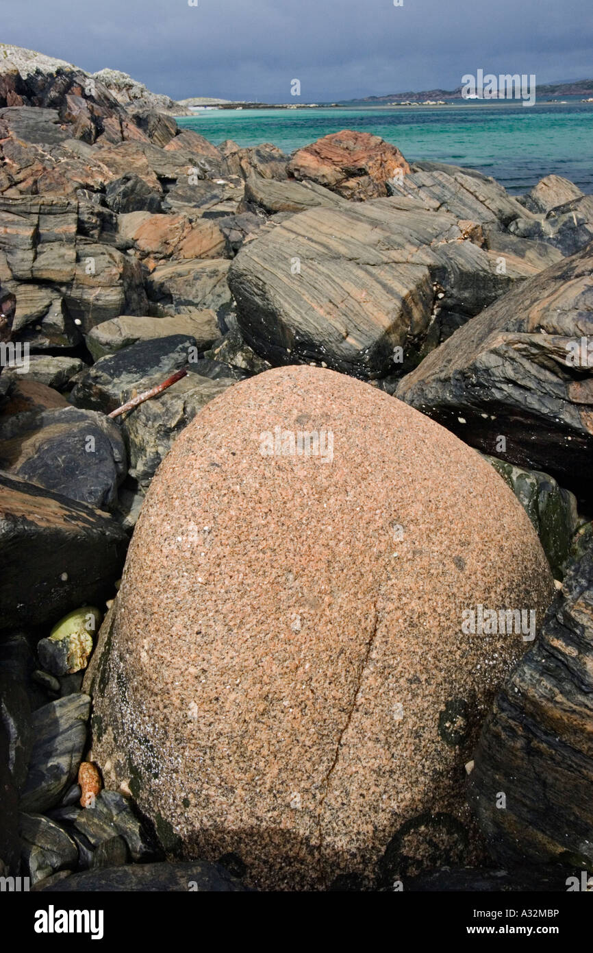 Eine abgerundete Granitblock hebt sich von den Balck Felsen auf die SW Küste Iona Stockfoto