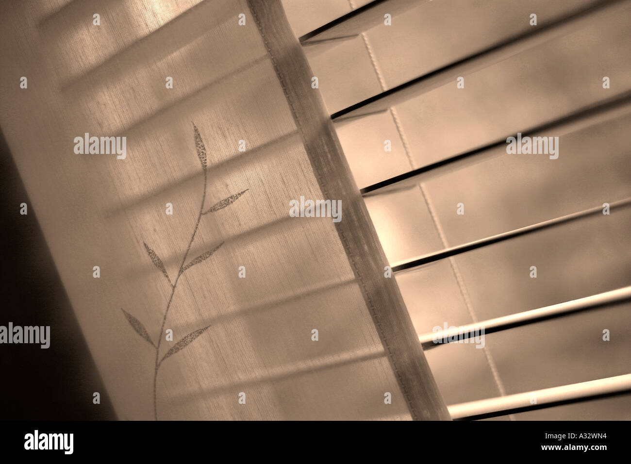 Nahaufnahme eines offenen Jalousien, die Hälfte von gemusterten Gardinen abgedeckt Stockfoto