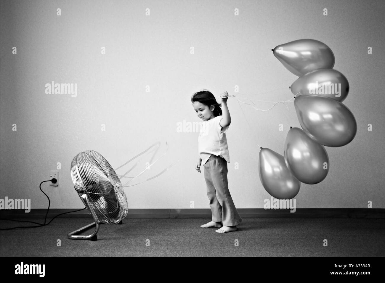 Kind hält Luftballons vor Ventilator Stockfoto