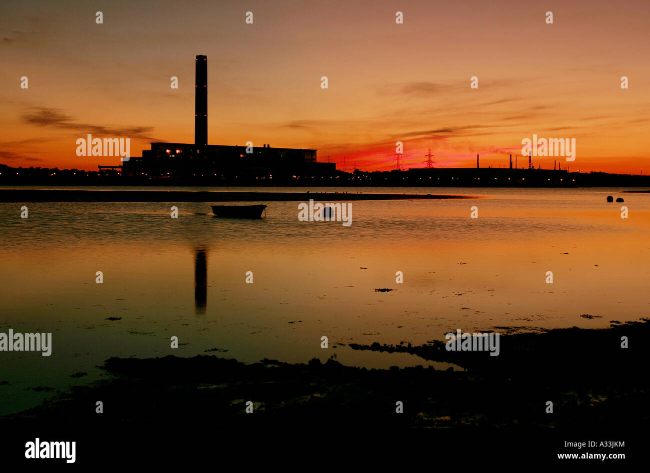 Marchwood Kraftwerk in Hampshire in der Silhouette bei Sonnenuntergang spiegelt sich im Bach Stockfoto