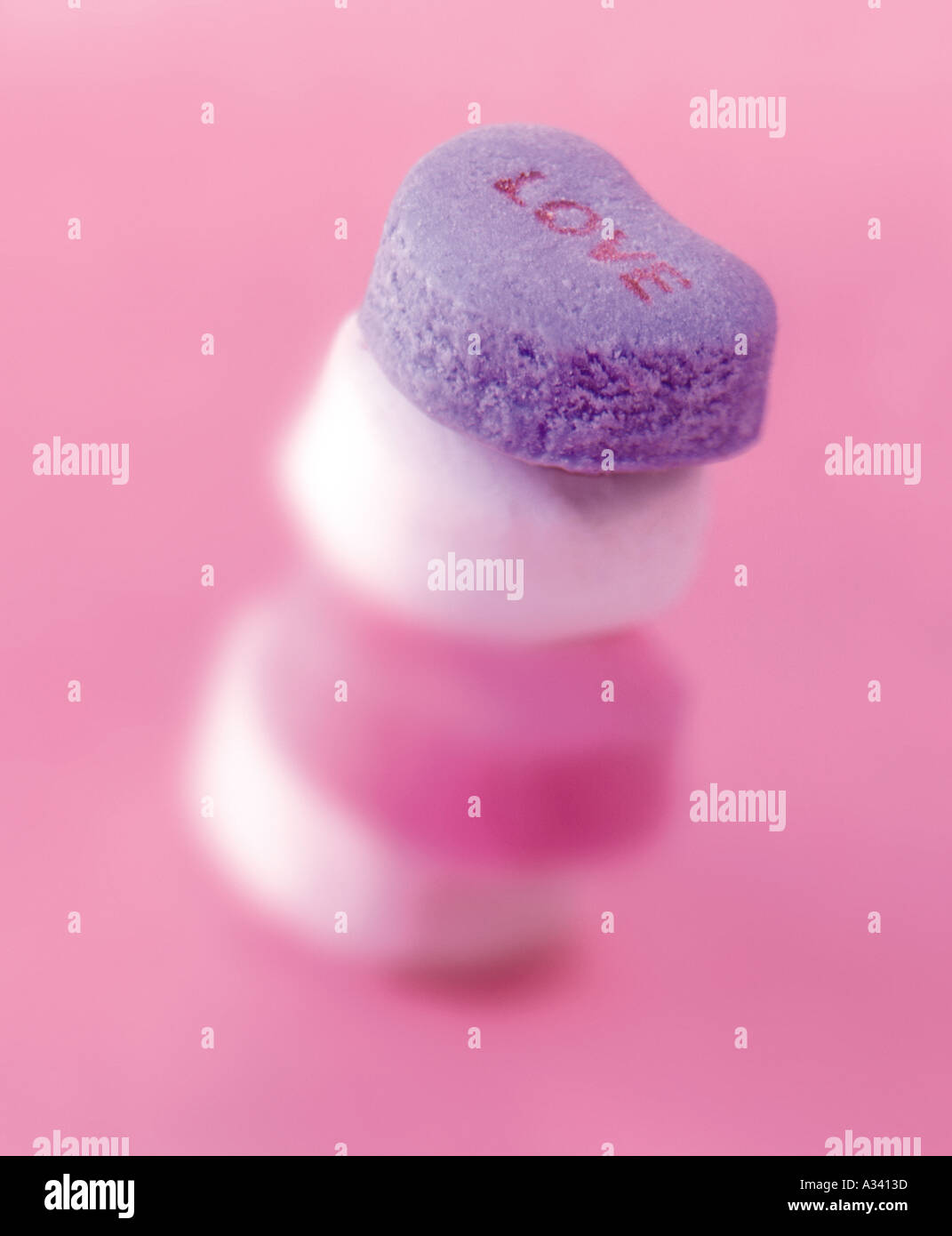 Herzförmige Bonbons mit dem Wort Liebe auf rosa Hintergrund Stockfoto
