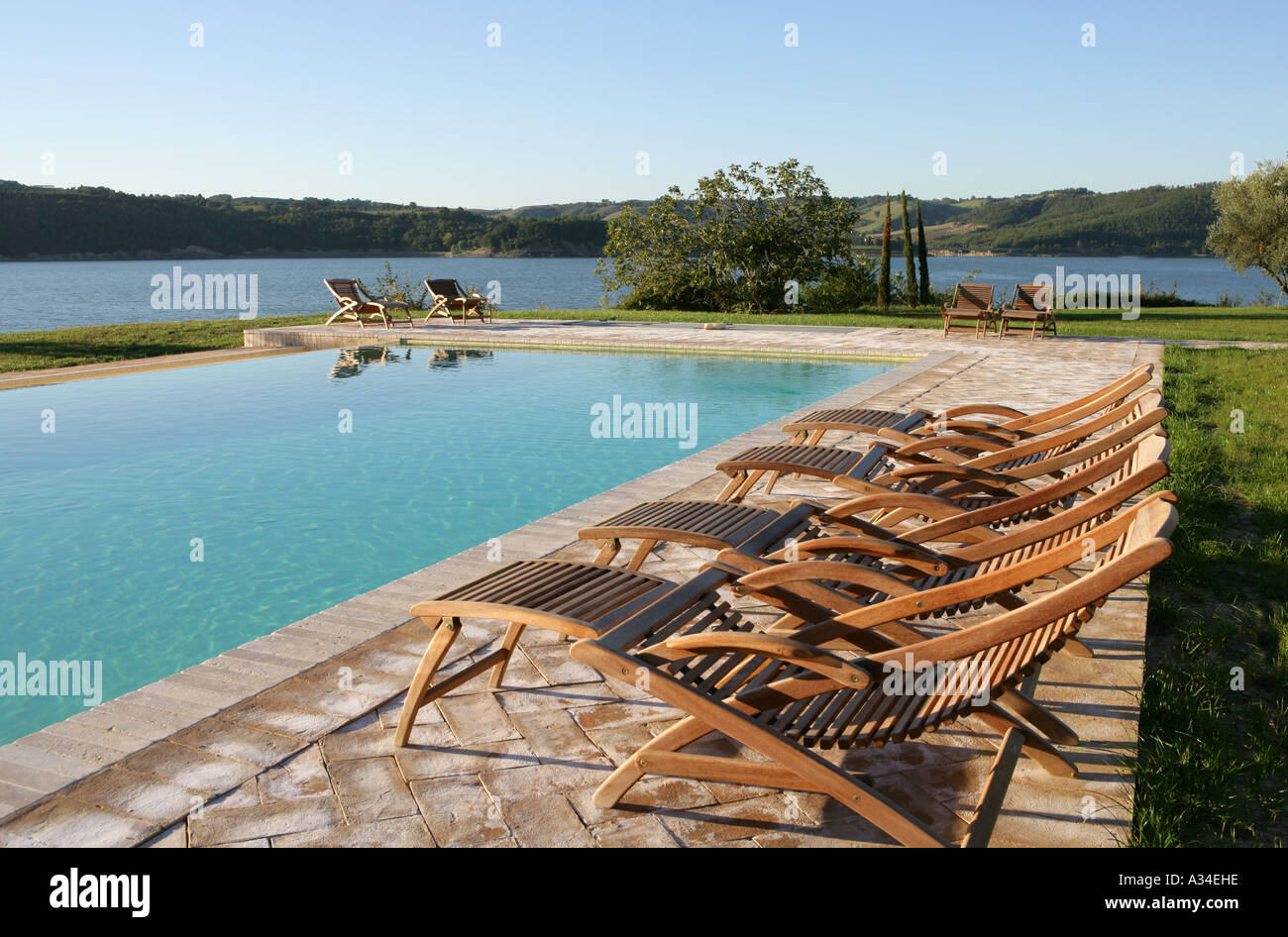 Schwimmbad und hölzerne Liegestühle mit See Blick, Umbrien, Italien Stockfoto