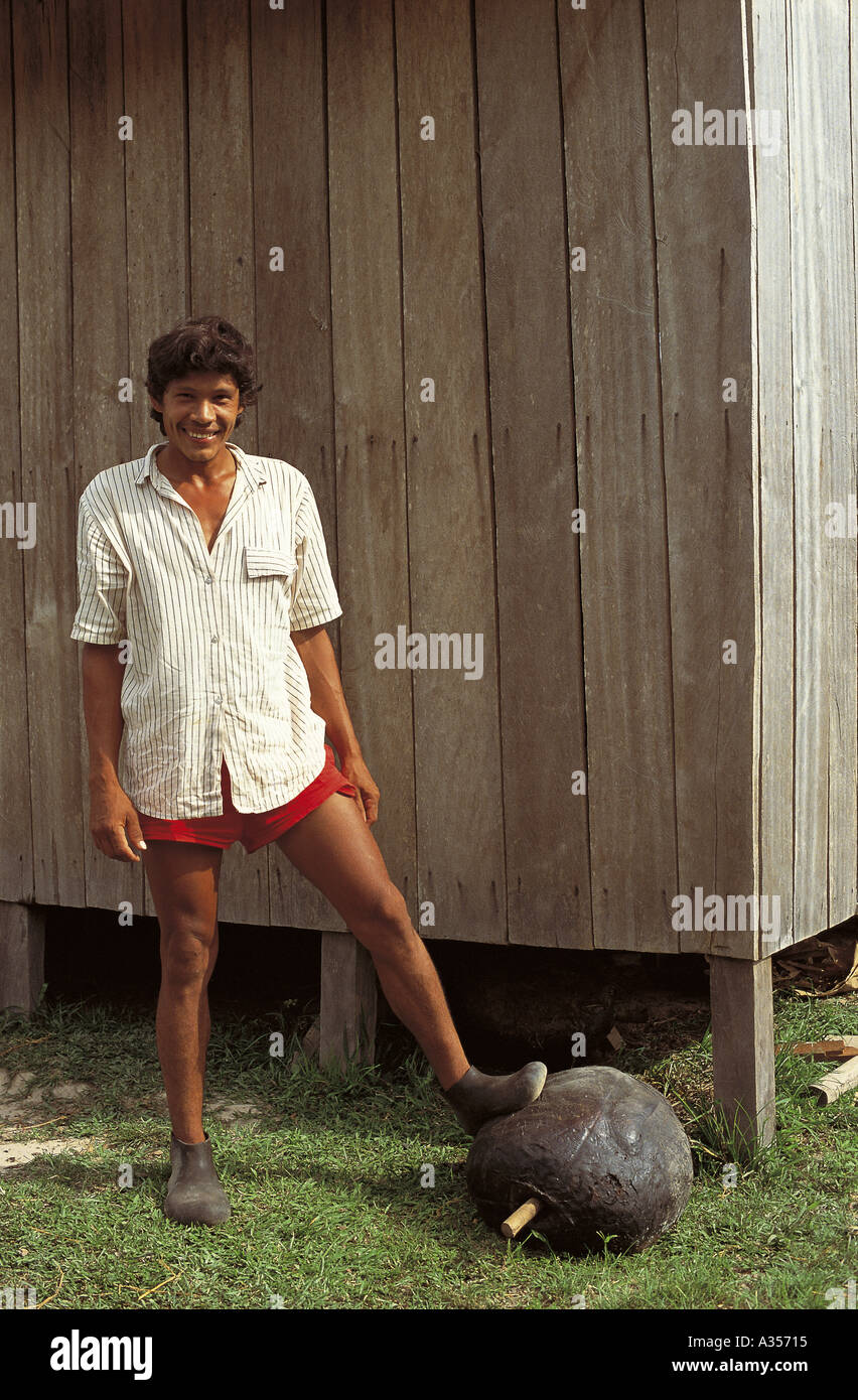 Acre Brasilien Gummizapfer tragen Gummischuhe mit seinem Fuß auf einem Ball geräuchertem Gummi vor seinem Haus Stockfoto
