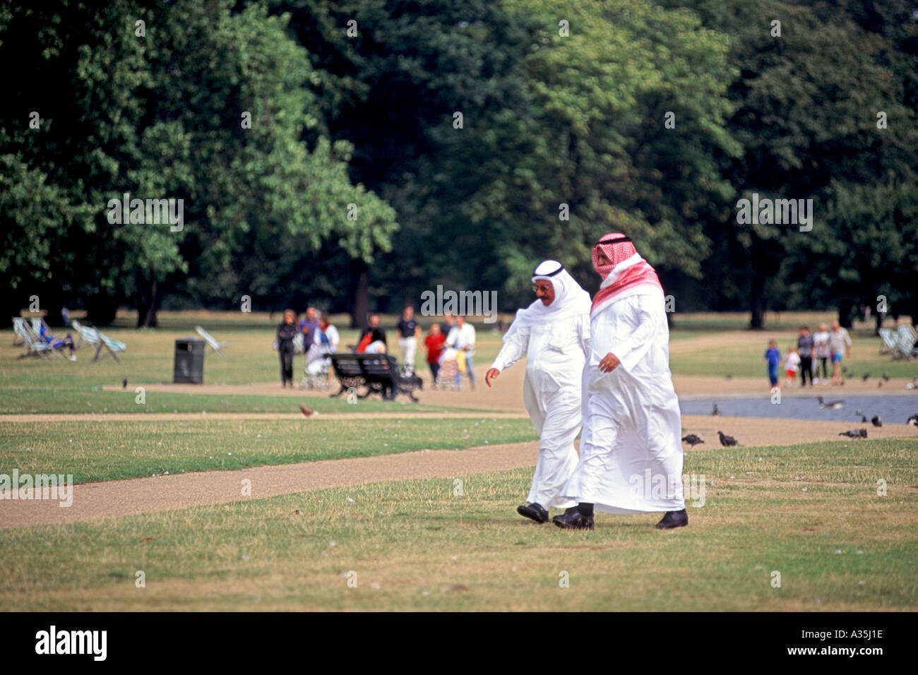 Zwei arabische Männer in traditionellen Outfits zu Fuß durch den Hyde Park in London. Stockfoto