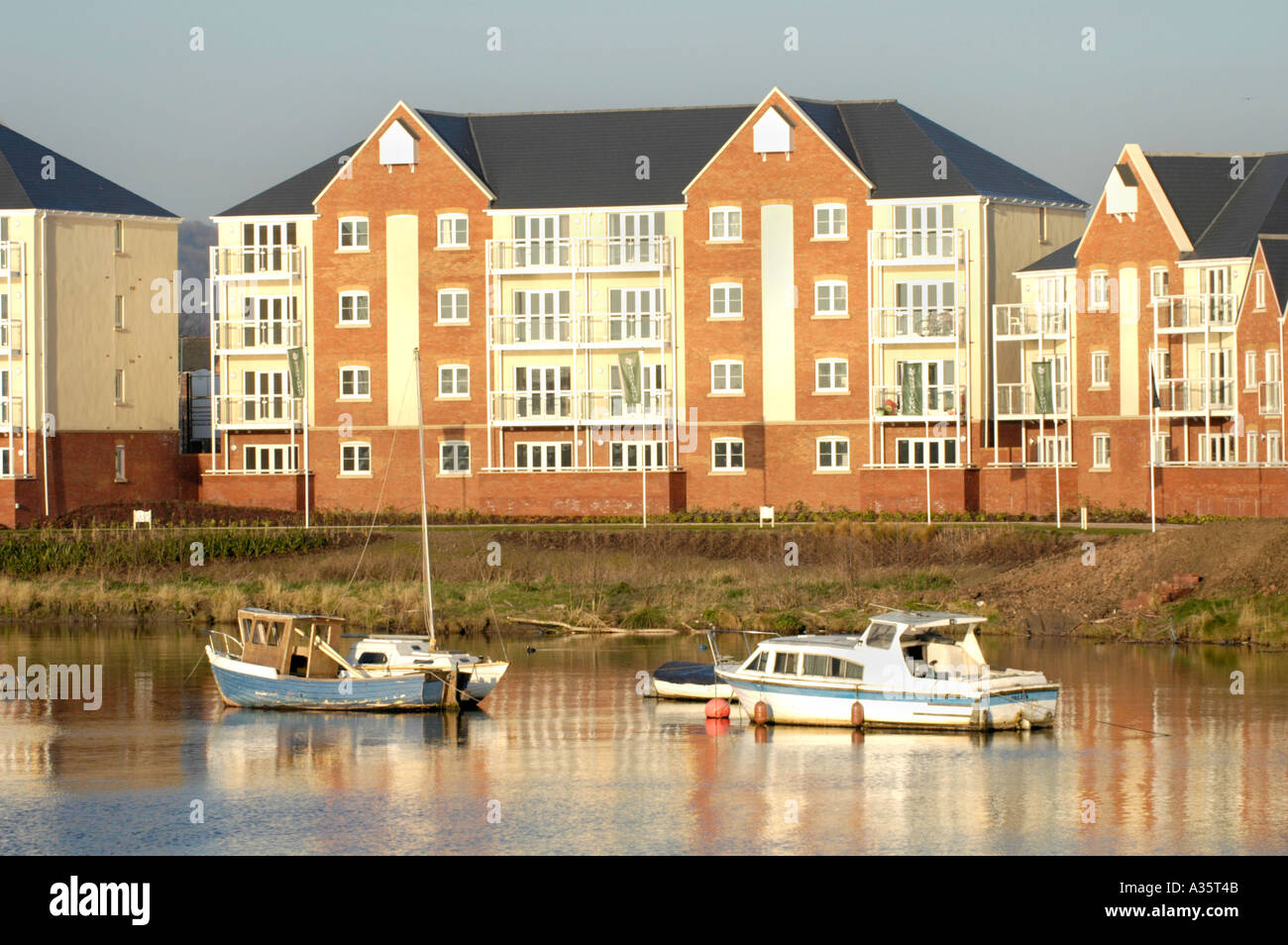 Moderne Mehrfamilienhäuser mit Blick auf Cardiff Bay Waterfront im frühen Morgenlicht mit festgemachten Boote Stockfoto