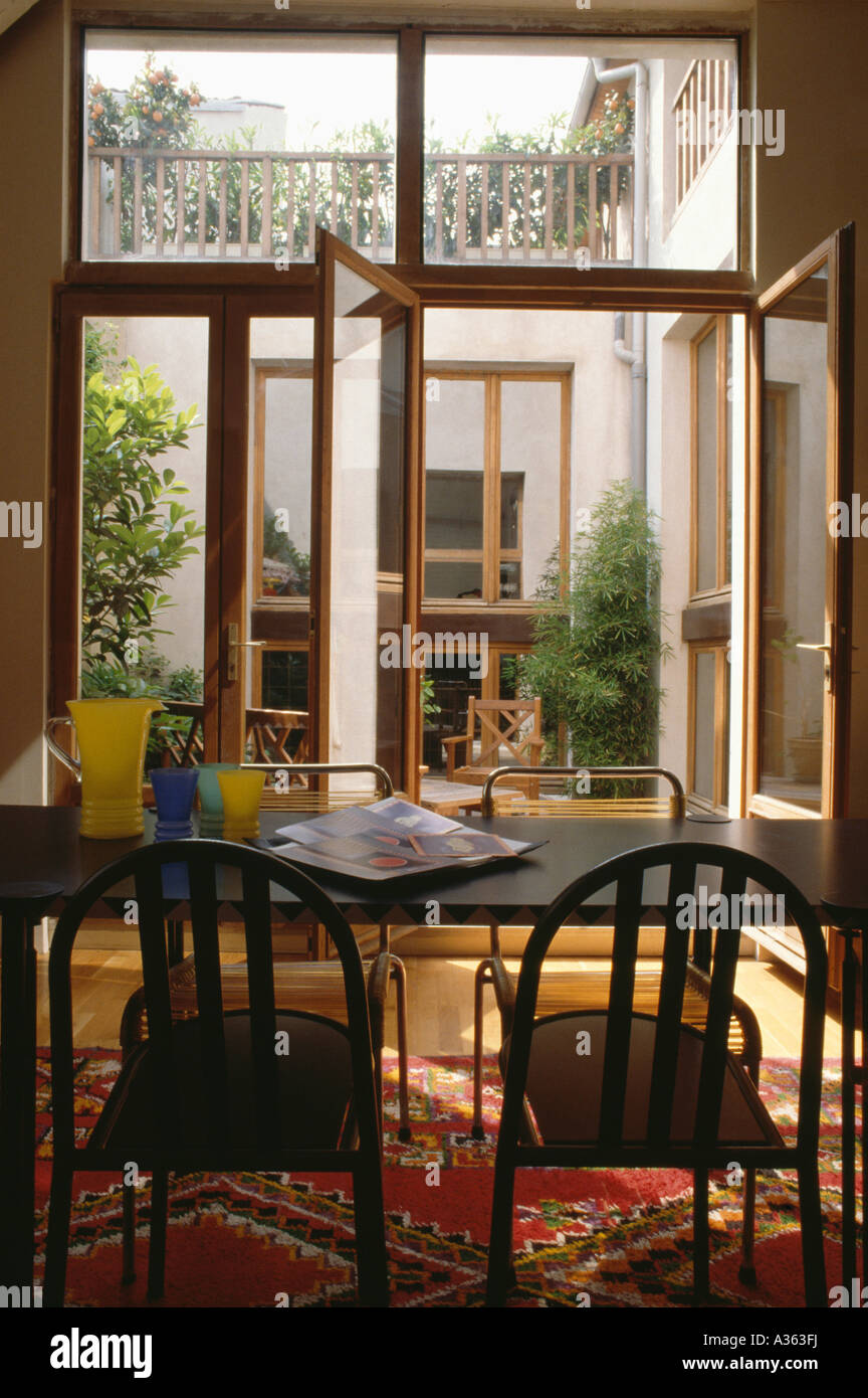 Schwarzer Esstisch Mit Stuhlen Im Modernen Speisesaal Mit Offenen Glas Terrassenturen Zum Kleinen Innenhof Stockfotografie Alamy