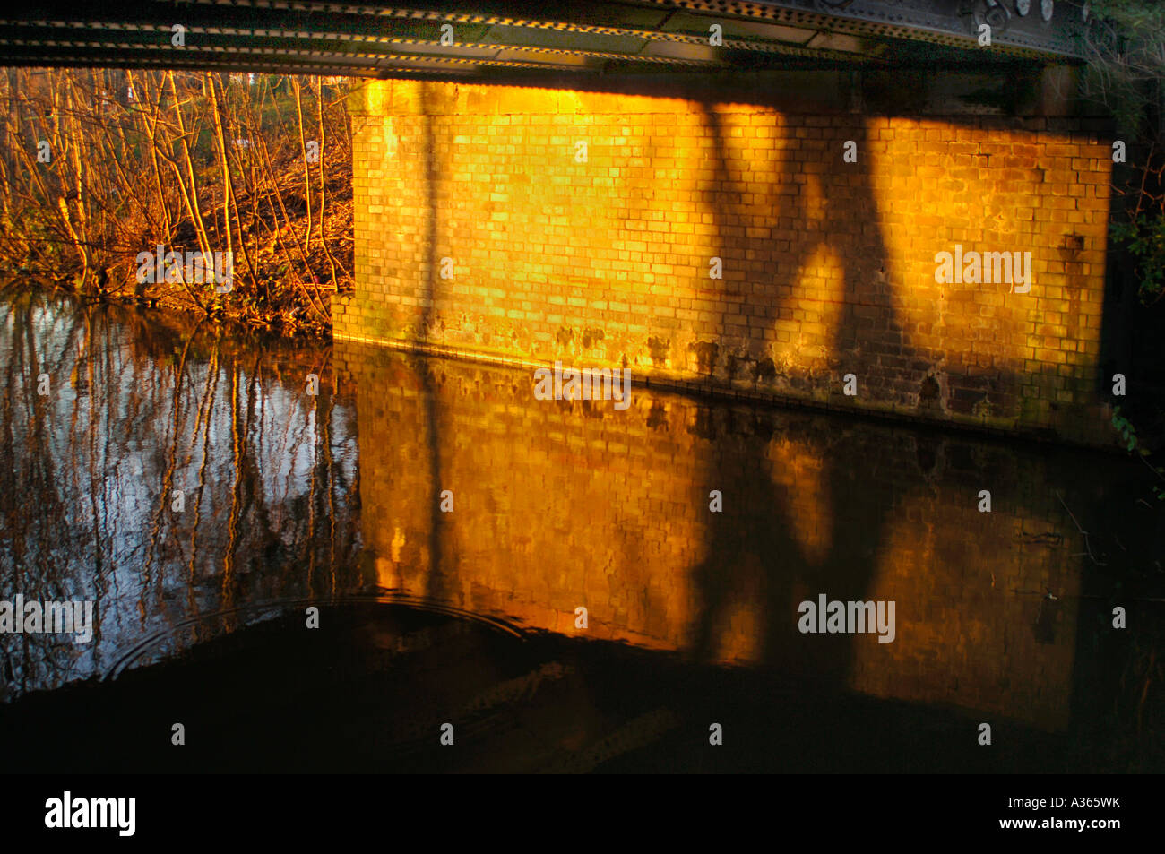 Dämmerung Sonnenlicht beleuchtet die Unterseite einer Brücke, über den Cauldon Kanal In Staffordshire. Stockfoto