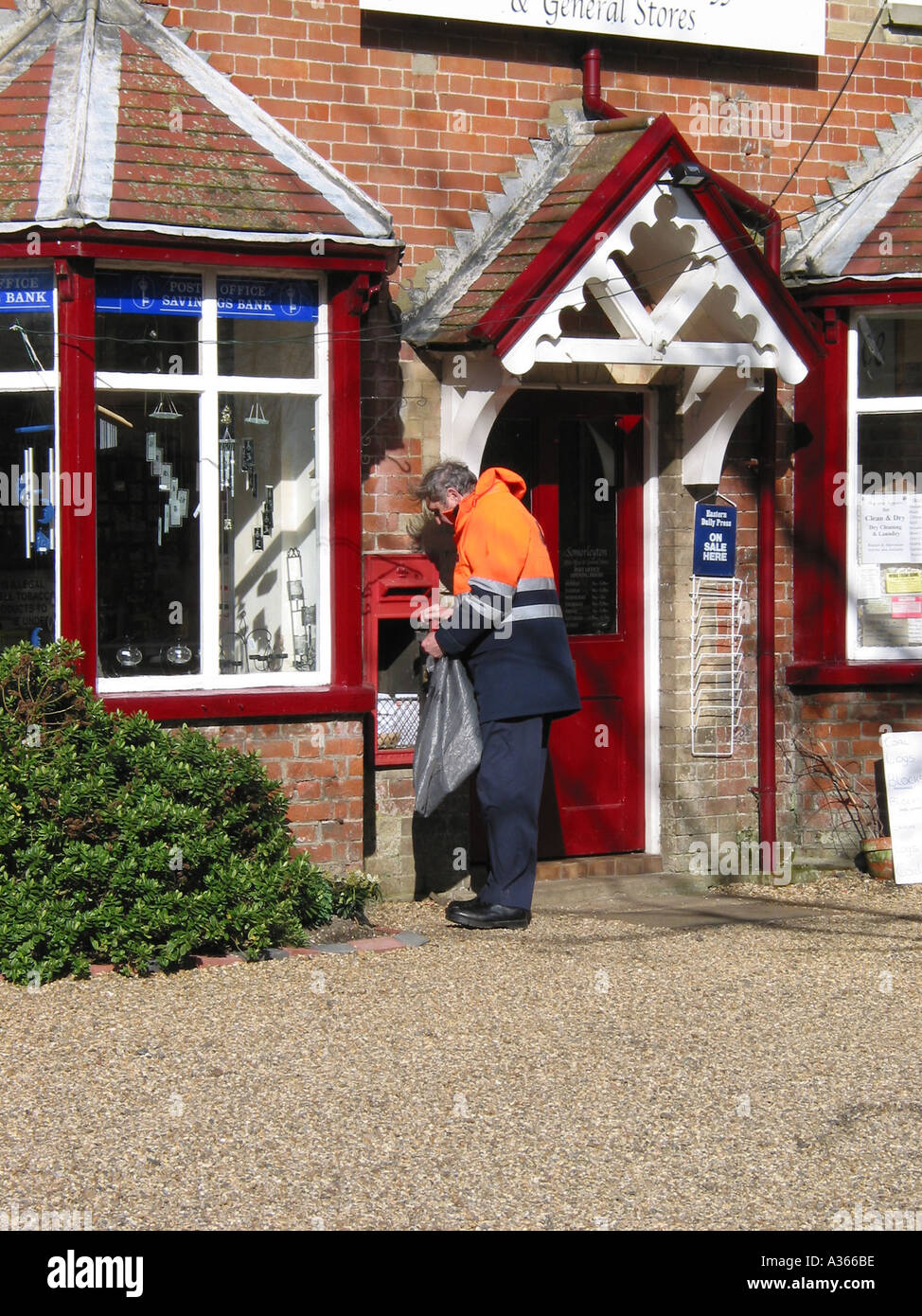 Postbote, die Post von einem traditionellen englischen Dorf Posting Box, England, Vereinigtes Königreich Stockfoto