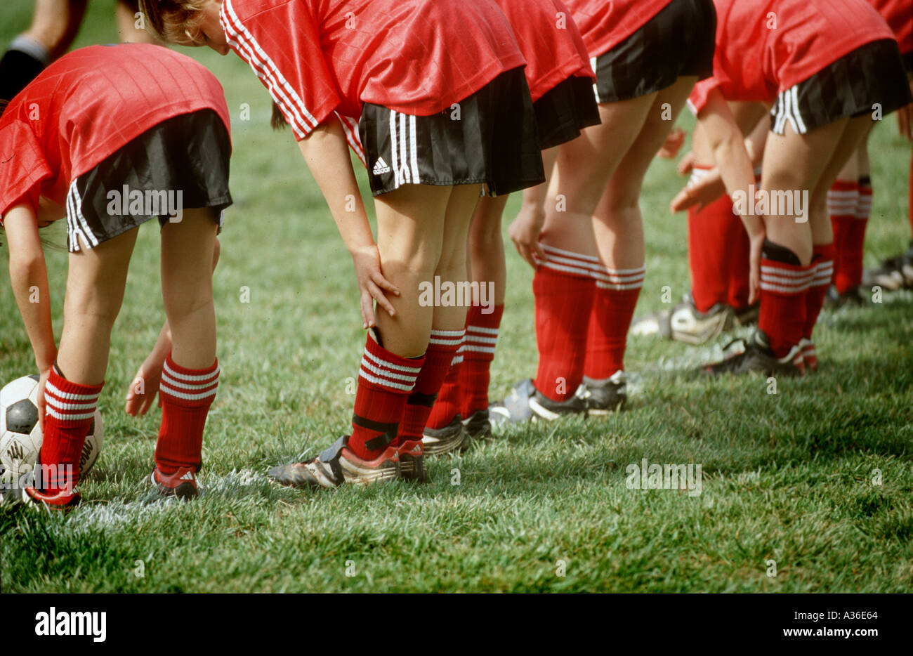 Eine Reihe von weiblichen Fußballer sind aufgereiht und beugte sich über wie sie erstrecken sich auf einem grünen Fußballfeld Stockfoto