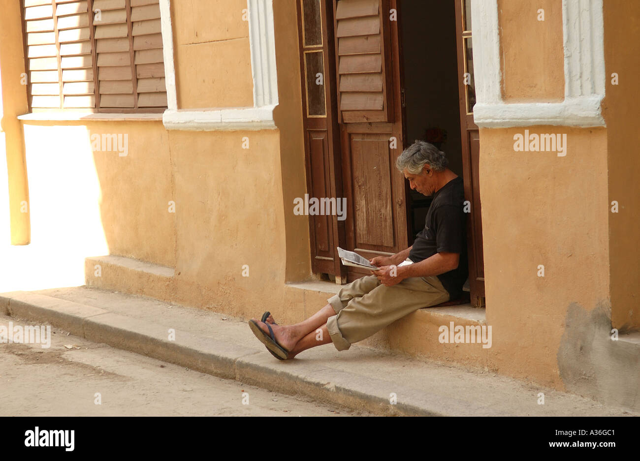 Mann sitzt in einem Hauseingang Zeitunglesen Havanna Kuba Stockfoto
