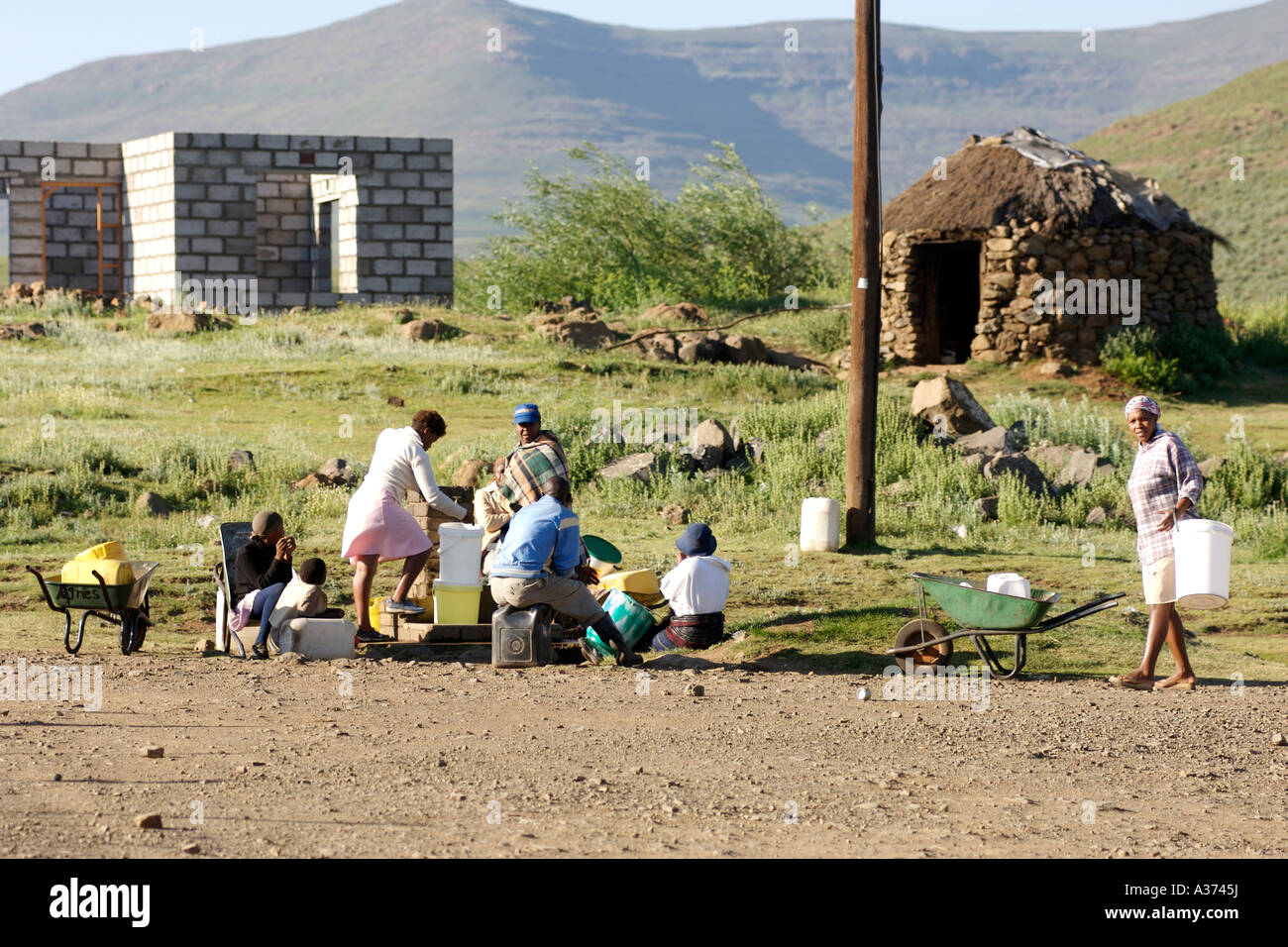 Dorfbewohner versammeln sich, um Wasser am kommunalen Hahn im Dorf Semonkong in Lesotho zu sammeln. Stockfoto