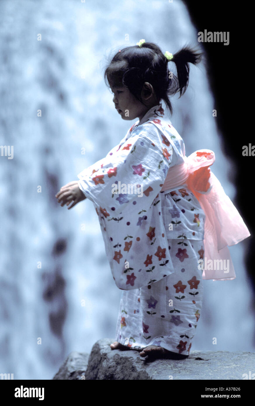 Japanische Mädchen in traditioneller Kleidung vor Wasserfall Stockfoto