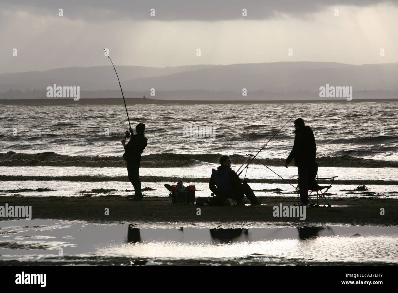 Seefischer kämpfen gegen die herannahenden Flut an einem sonnigen Winternachmittag, Burnham-on-Sea, Somerset, Großbritannien. Stockfoto