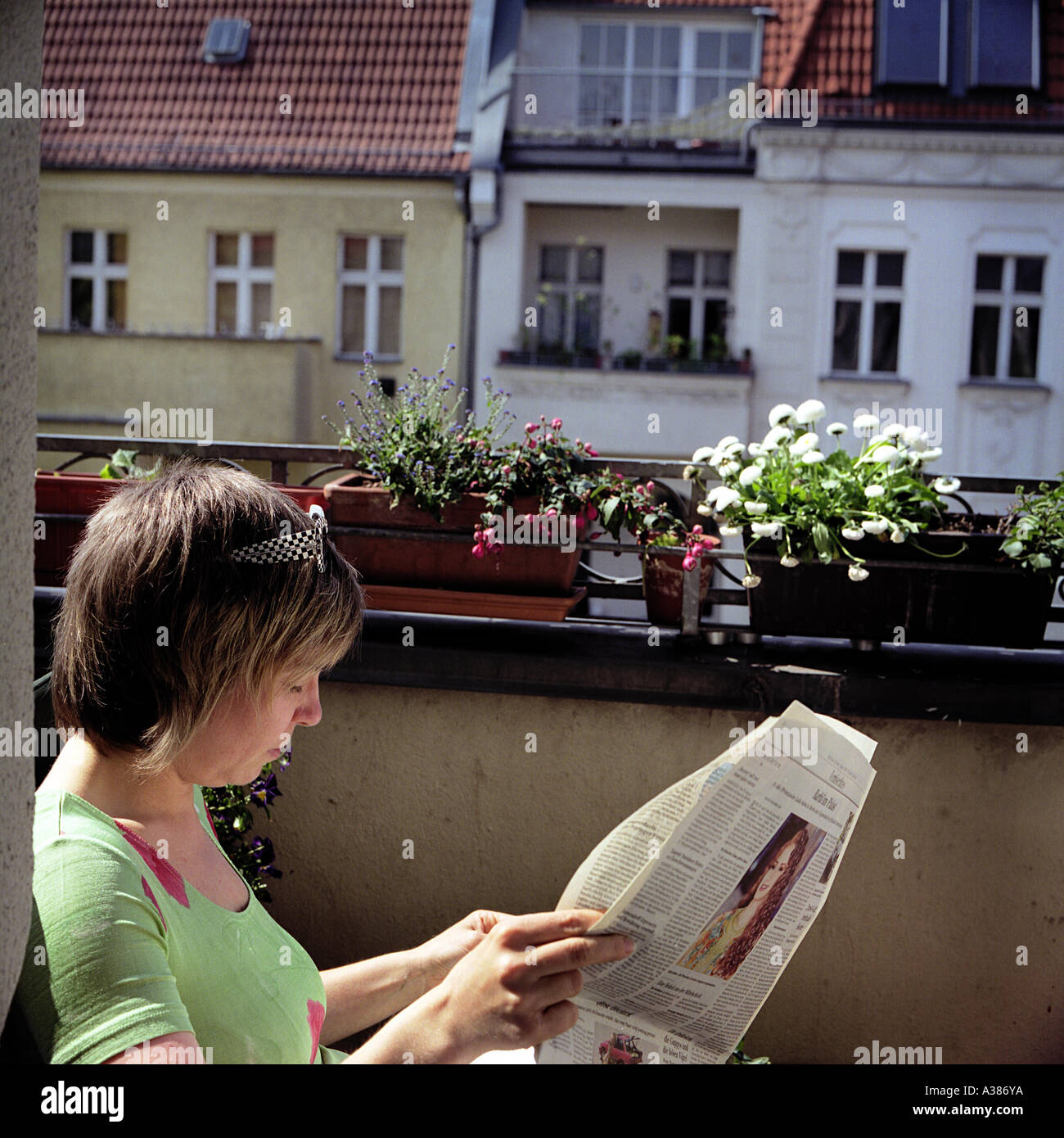 Danuta Schmidt liest eine Zeitung auf ihrem Balkon Stockfoto