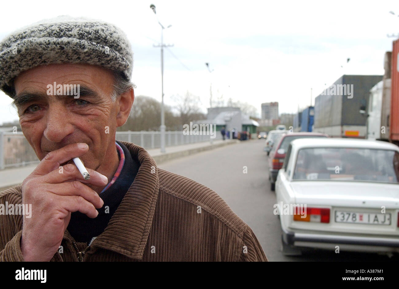 ein Alter Mann raucht eine Zigarette auf der Brücke während des Wartens an der Grenze von Europa nach Russland in Narva Stockfoto