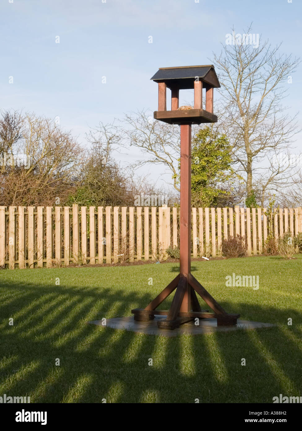 "VOGELHAUS" in einem Garten mit Zaun Schatten über Rasen aus tief stehender Sonne. Großbritannien UK Stockfoto