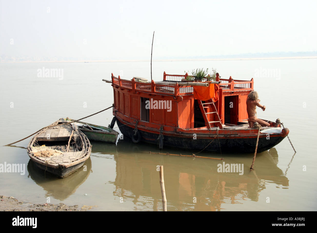 Sadhu waschen auf seinem Boot festgemacht am Ufer des Flusses Ganges, Varanasi, Uttar Pradesh, Indien Stockfoto