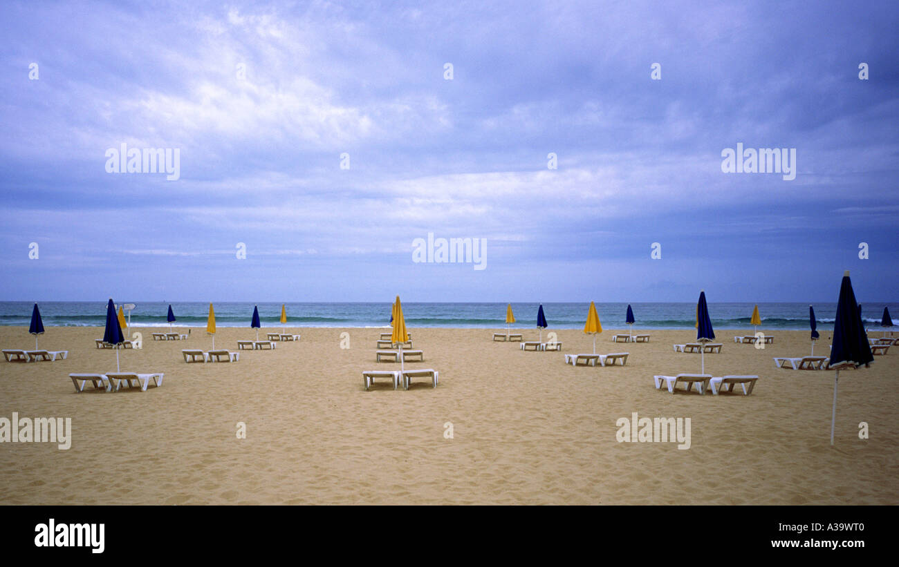 Leerer Strand mit Sonnenschirmen und Liegestühlen an der Algarve an der südlichen Küste von Portugal Stockfoto