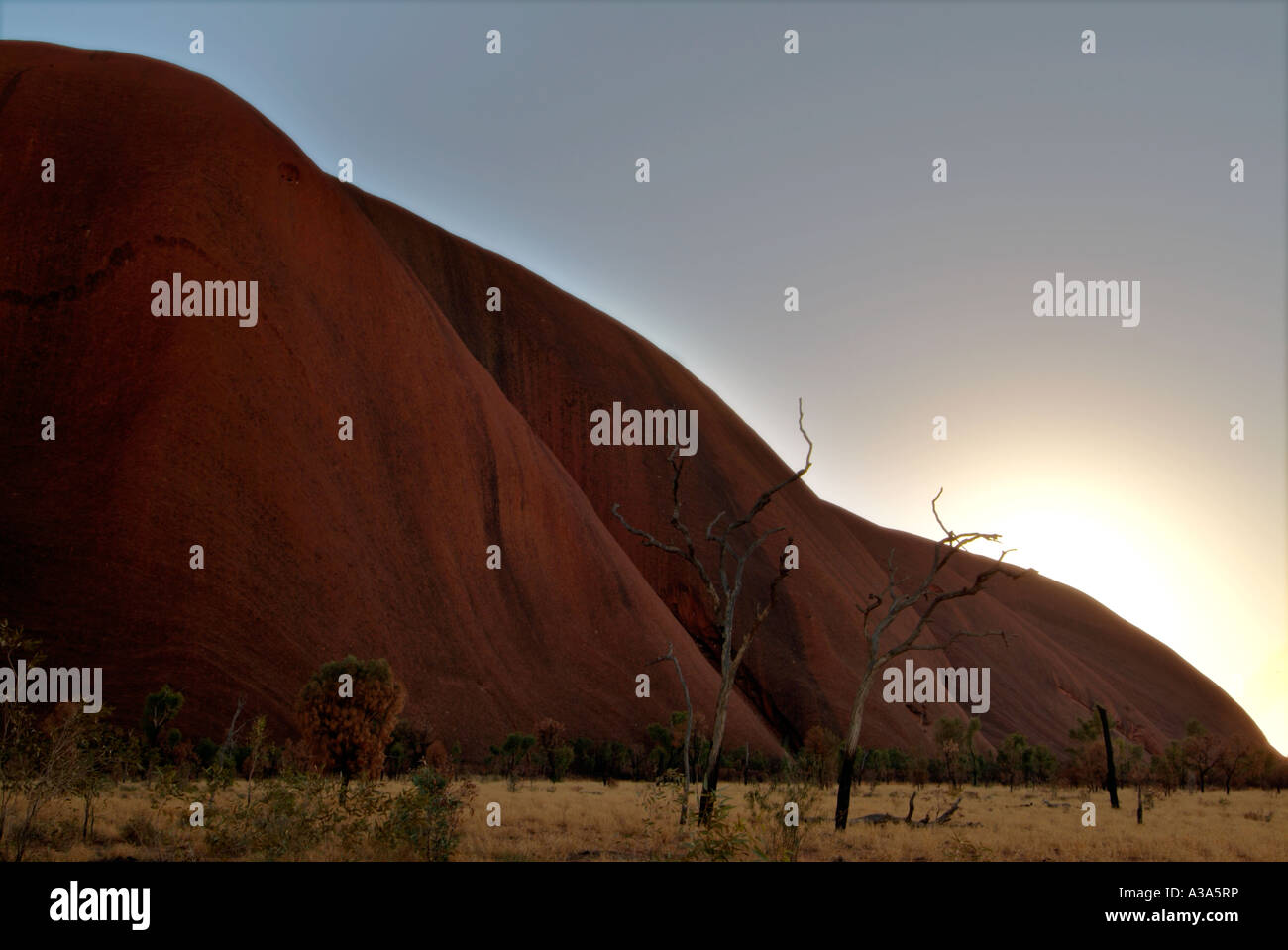 Dramatische und andere Ansicht des Ayers Rock bei Sonnenaufgang entlang der Basis gehen um Uluru gesehen Stockfoto