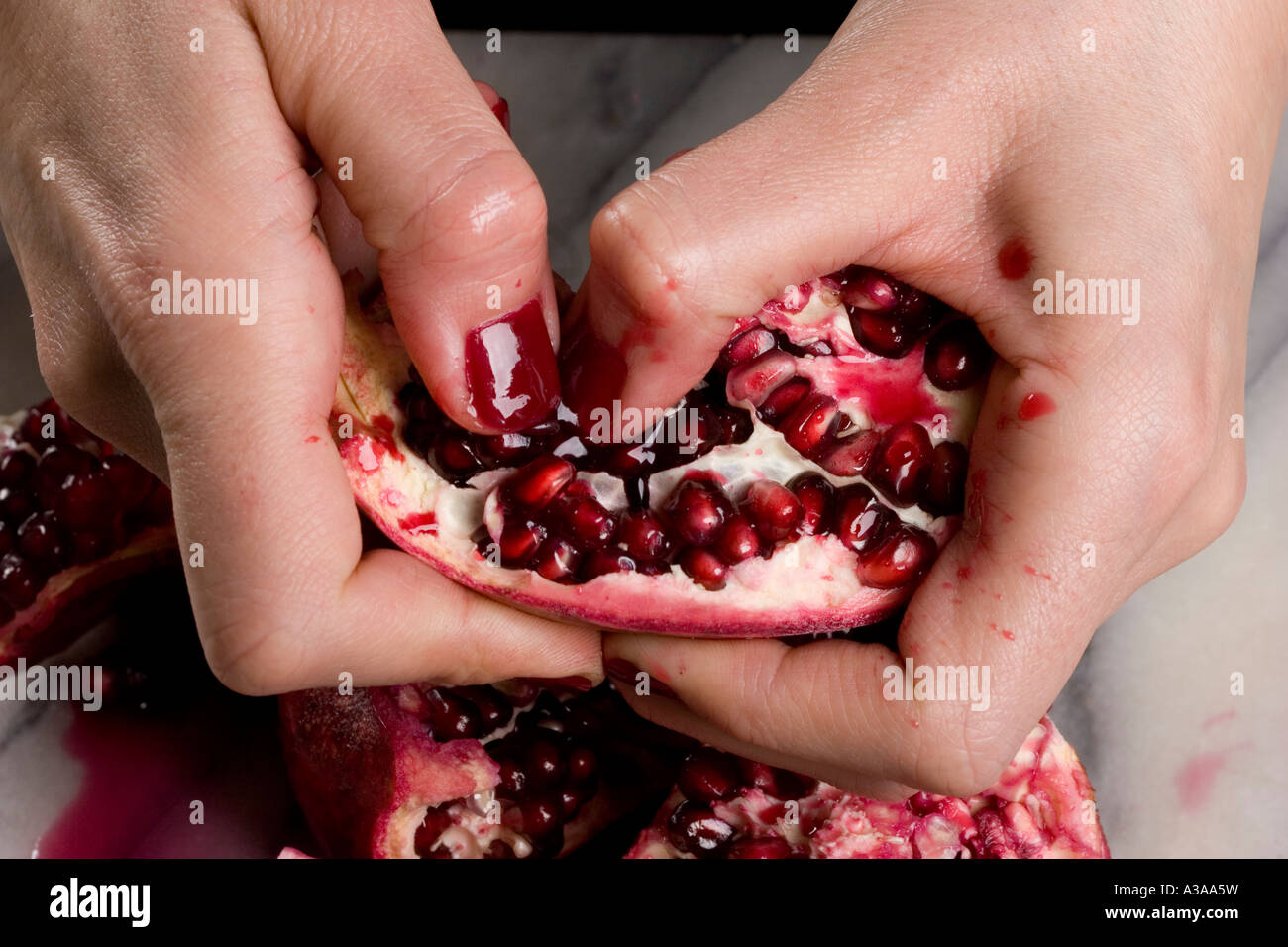 Bild von einer Frauenhand Halbierung der Granatapfel-Frucht Stockfoto