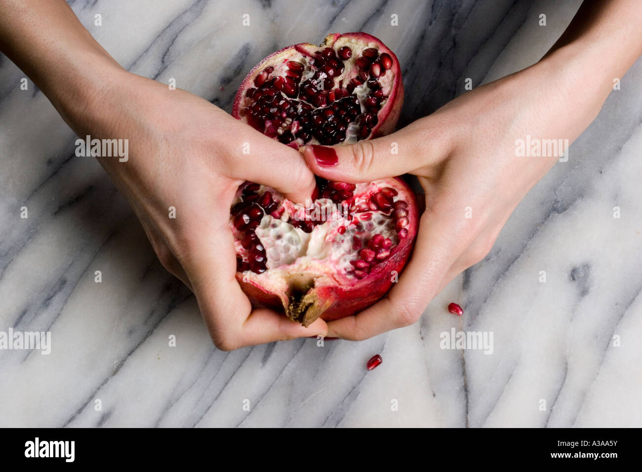 Bild von einer Frauenhand Halbierung der Granatapfel-Frucht Stockfoto